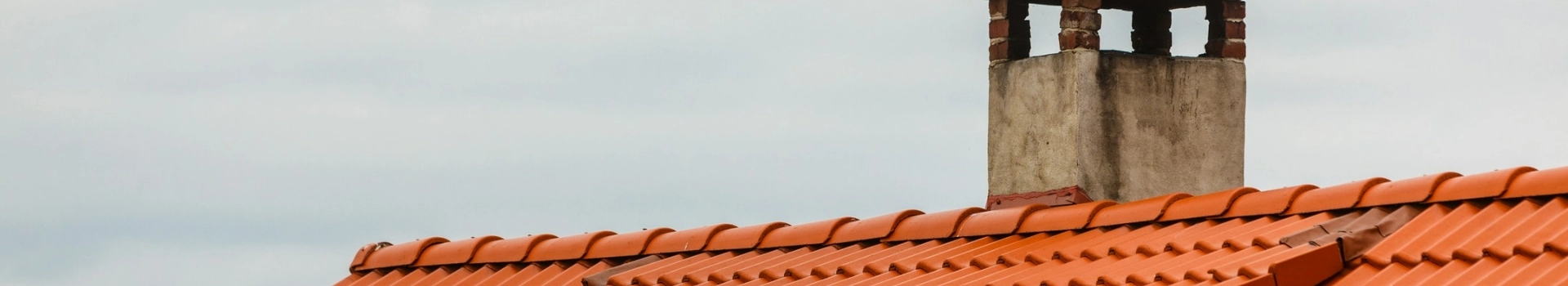 Komin na dachu pokrytym pomarańczową dachówką