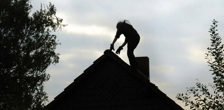 Sylwetka kominiarza na dachu